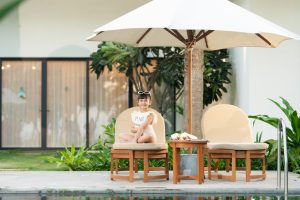 em bé ngồi trên ghế cạnh bể bơi trong khu nghỉ dưỡng